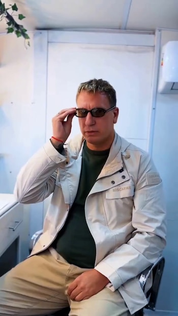 Maxi López sentado con una chaqueta beige y camiseta verde mientras acomoda sus anteojos de sol con la mano derecha