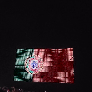 Pantalla de luces LED muestra la bandera de Portugal con franjas verde y roja, y el escudo nacional central, sobre fondo oscuro