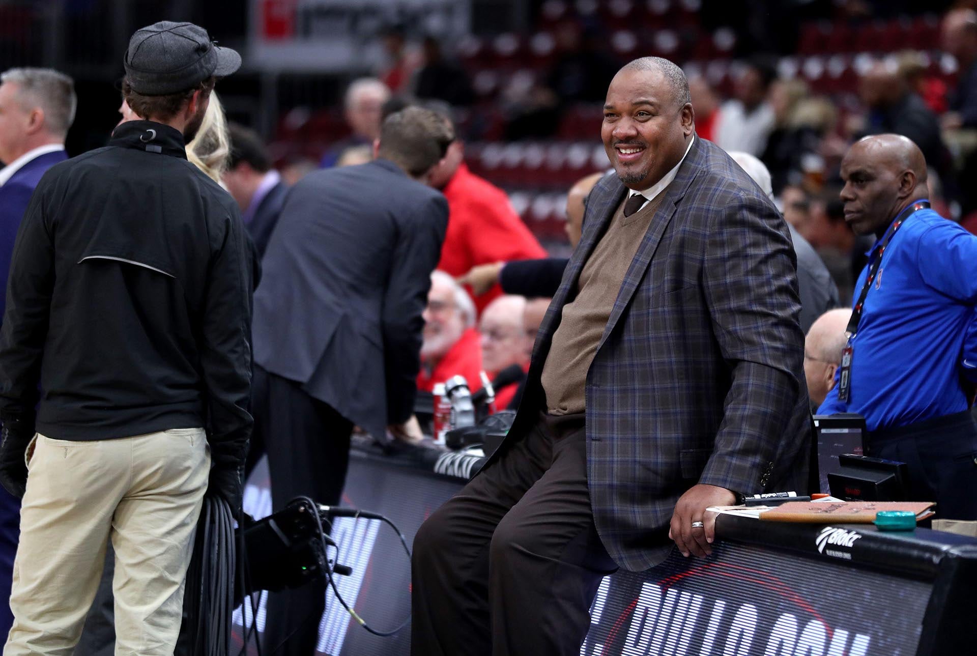 Stacey King, el ex jugador de la NBA y popular comentarista deportivo, sonríe mientras observa la acción desde la cancha durante un partido de baloncesto profesional. (Grosby)