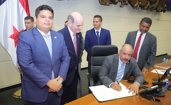 El presidente de la Asamblea Nacional, Jorge Herrera, firma la aprobada ley de sustancia económica. Observa de pie, el ministro de Economía y Finanzas, Felipe Chapman (izq).