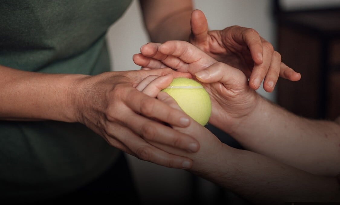 Kriszanac gana movilidad en sus manos presionando una pelota de tenis (Captura de video)