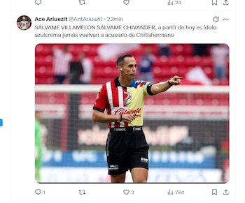 Un árbitro de fútbol con una camiseta dividida en los colores amarillo del Club América y rojo y blanco de Chivas, apuntando con su mano derecha en un estadio