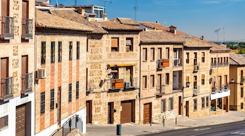 Fila de edificios de piedra y ladrillo con tejados de tejas, balcones de hierro forjado, ventanas y dos carteles de 'Se vende'.