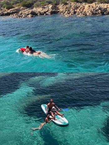 Hombre, mujer y bebé en el mar. Arriba, la pareja con scooter rojo. Abajo, los tres en tabla de paddle surf cerca de una costa rocosa