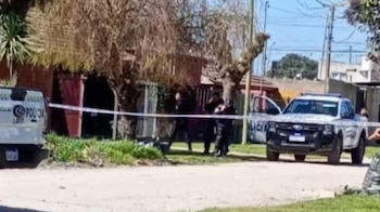 Dos patrulleros y varios policías permanecen detrás de una cinta de seguridad colocada frente a una vivienda