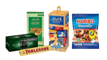 Empaques de chocolates After Eight, Toblerone y Lindt junto a una bolsa de golosinas Haribo Starmix sobre un fondo blanco