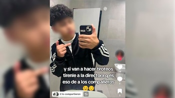 Joven con el rostro difuminado, vestido con una chaqueta deportiva negra, se toma una selfie en un baño, mostrando un teléfono y un mensaje de amenaza