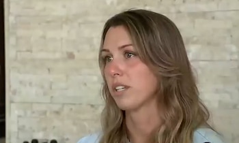 Una mujer caucásica de pelo rubio y ojos verdes, con una camisa azul claro, habla mirando hacia la derecha. El fondo es una pared de ladrillos