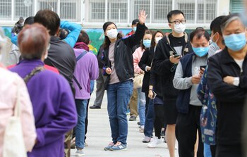 Un grupo de residentes de uno de los edificios en los que se ha localizado un último brote de la COVID-19 en Hong Kong hace turno para someterse a una prueba de coronavirus