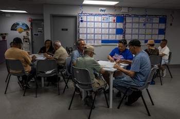 Un grupo de adultos mayores participa en actividades recreativas y juegos de mesa en un centro comunitario de Nueva York, espacios que cumplen un rol clave en la socialización, el bienestar emocional y el combate contra el aislamiento en la población senior.