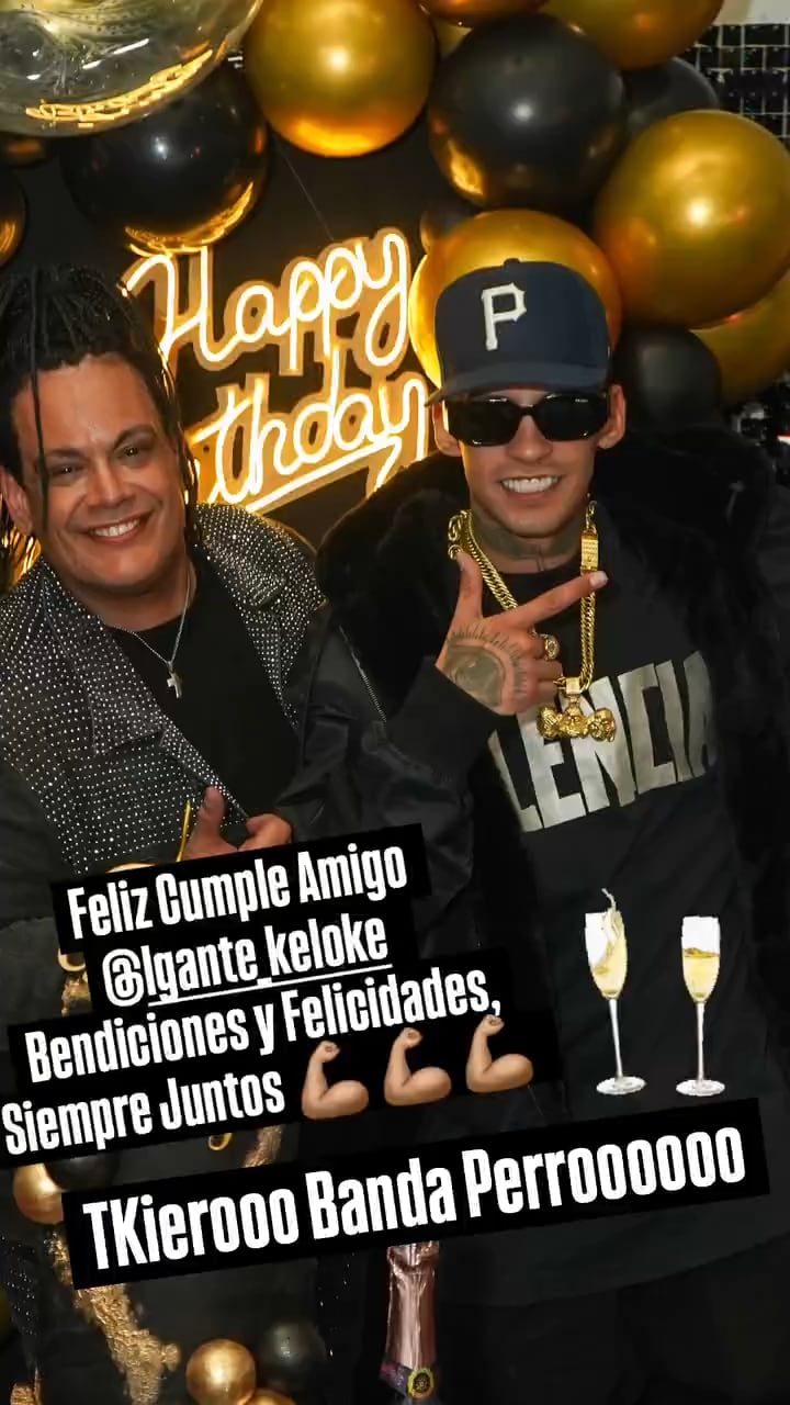 El reconocido cantante L-Gante celebra su cumpleaños junto a un amigo, sonriendo ante una decoración festiva de globos dorados y negros y un cartel de neón.