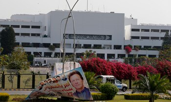 Pakistani paramilitary troops patrol near a billboard with the picture of Pakistan's Prime Minister Imran Khan is displayed outside the National Assembly, in Islamabad, Pakistan, Sunday, April 3, 2022. Pakistan's embattled prime minister faces a no-confidence vote in Parliament on Sunday and the opposition said it has the numbers to win after Imran Khan's allies and partners in a fragile coalition abandoned him. (AP Photo/Anjum Naveed)