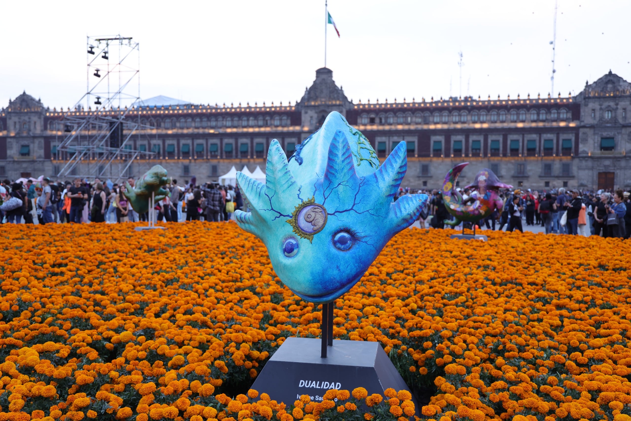 Una escultura rodeada por flores de cempasúchil forma parte de la megaofrenda instalada en el Zócalo de la Ciudad de México frente al Palacio Nacional. (Gobierno CDMX)