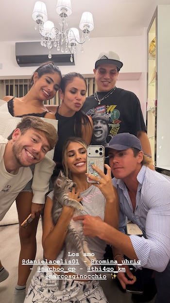 Seis jóvenes, cuatro mujeres y dos hombres, sonríen mientras posan para una selfie en un interior; una mujer al frente sostiene un gatito gris