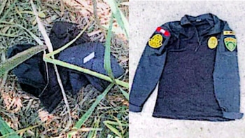 Una prenda negra entre la vegetación y una camisa táctica oscura con insignias policiales extendida sobre una superficie plana