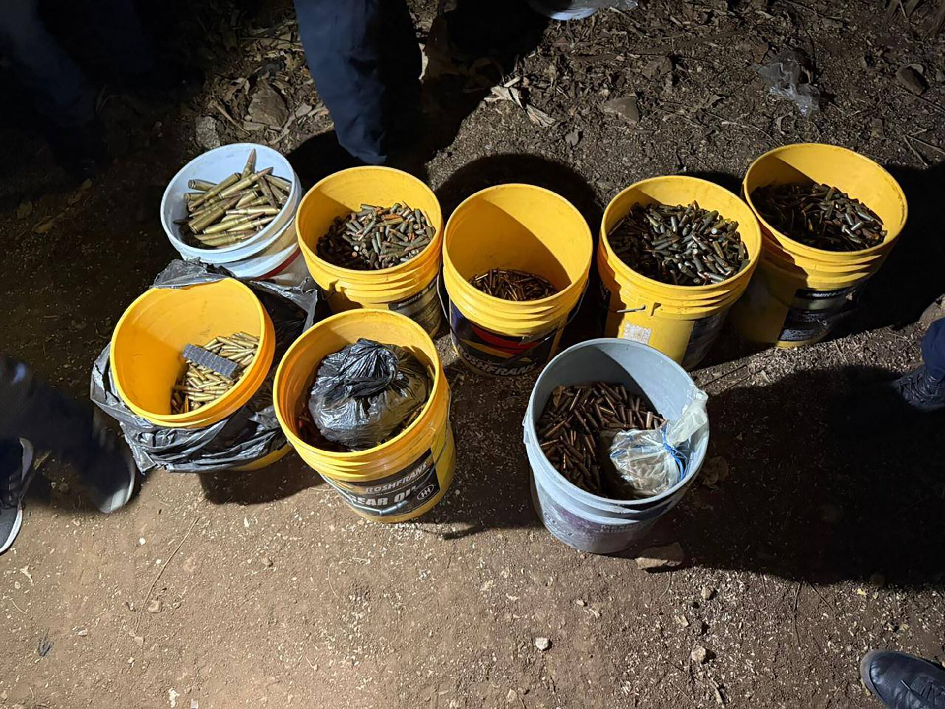 Durante un operativo en Huehuetenango, Guatemala, se descubrieron y confiscaron múltiples cubetas llenas de municiones, granadas y dinamita en un terreno oscuro. (Ministerio Público de Guatemala)