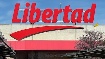 Vista frontal de un edificio con un gran cartel rojo que dice "Libertad" en letras mayúsculas, sobre una estructura roja y hormigón gris, bajo un cielo azul