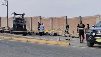 Un grupo de policías y peritos investigan una escena del crimen en la avenida Néstor Gambetta, con cinta amarilla, un vehículo de construcción y un automóvil negro visibles