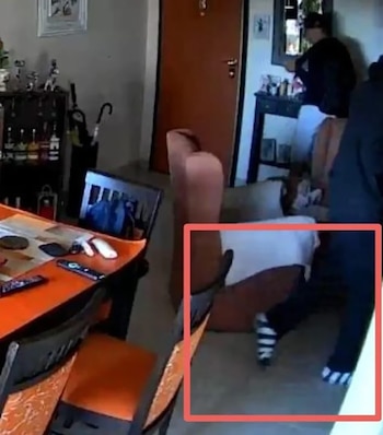 Parte inferior del cuerpo de una persona con pantalones oscuros y calcetines de rayas blancos y negros, vista dentro de una habitación