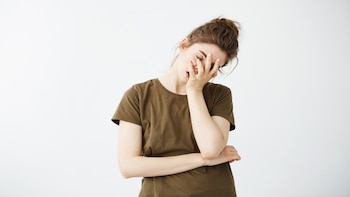 Mujer con fatiga tiene la mano en el rostro y los ojos cerrados (Freepik)