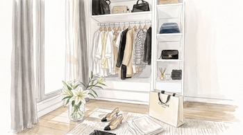 Un vestidor con ropa colgada, estantes con prendas dobladas, bolsos, zapatos, una bolsa de compras, un jarrón con flores, y un difusor de aroma.