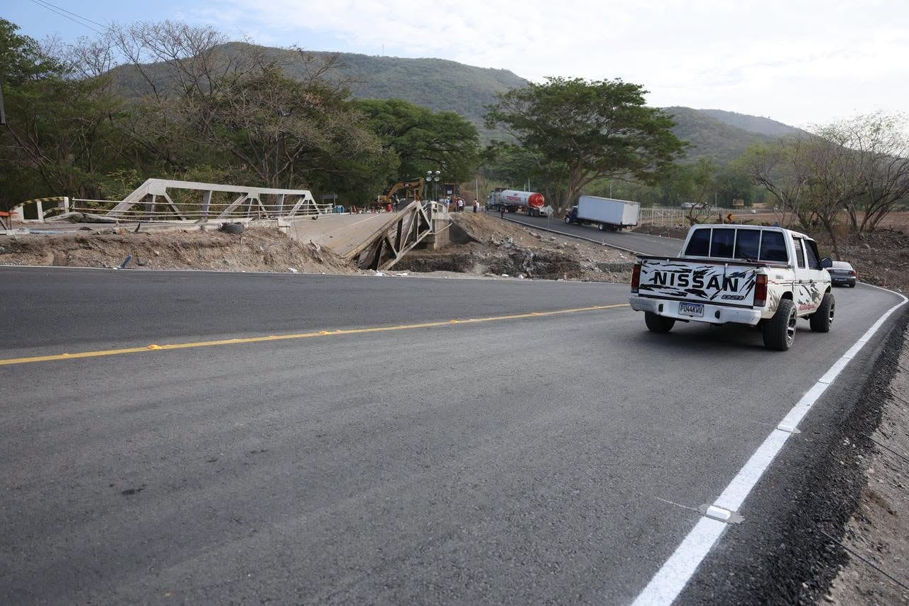 Una camioneta blanca circula por un tramo asfaltado habilitado a un costado de la estructura derrumbada de un puente. (Ministerio de Comunicaciones, Infraestructura y Vivienda)