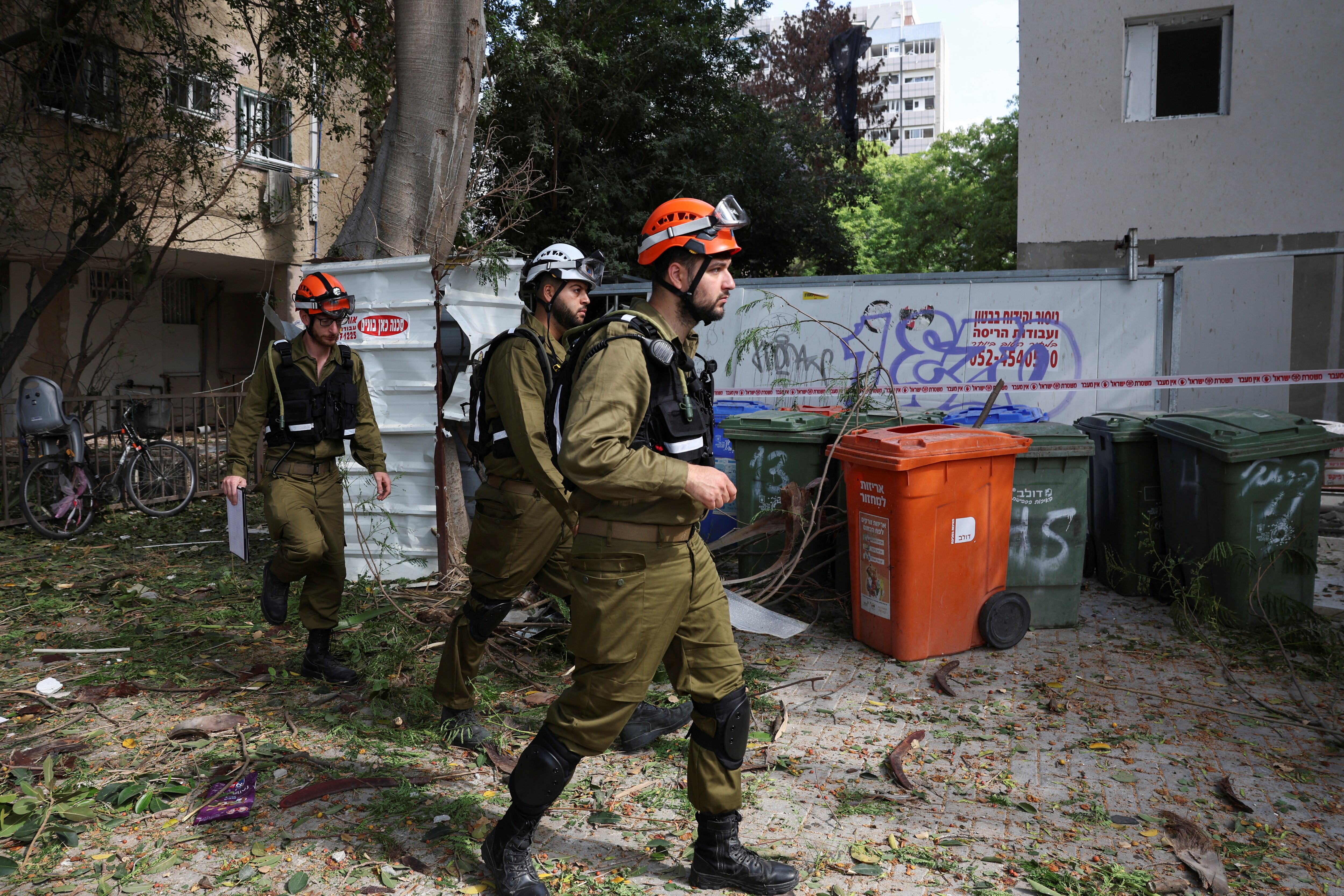 Bomberos israelíes recorren un barrio en las afueras de Tel Aviv, tras los ataques aéreos ejecutados por Irán