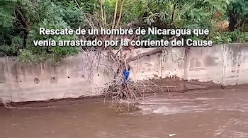Un hombre sobre unas ramas junto a un muro de concreto en un cauce de agua marrón con vegetación de fondo y un texto superpuesto.