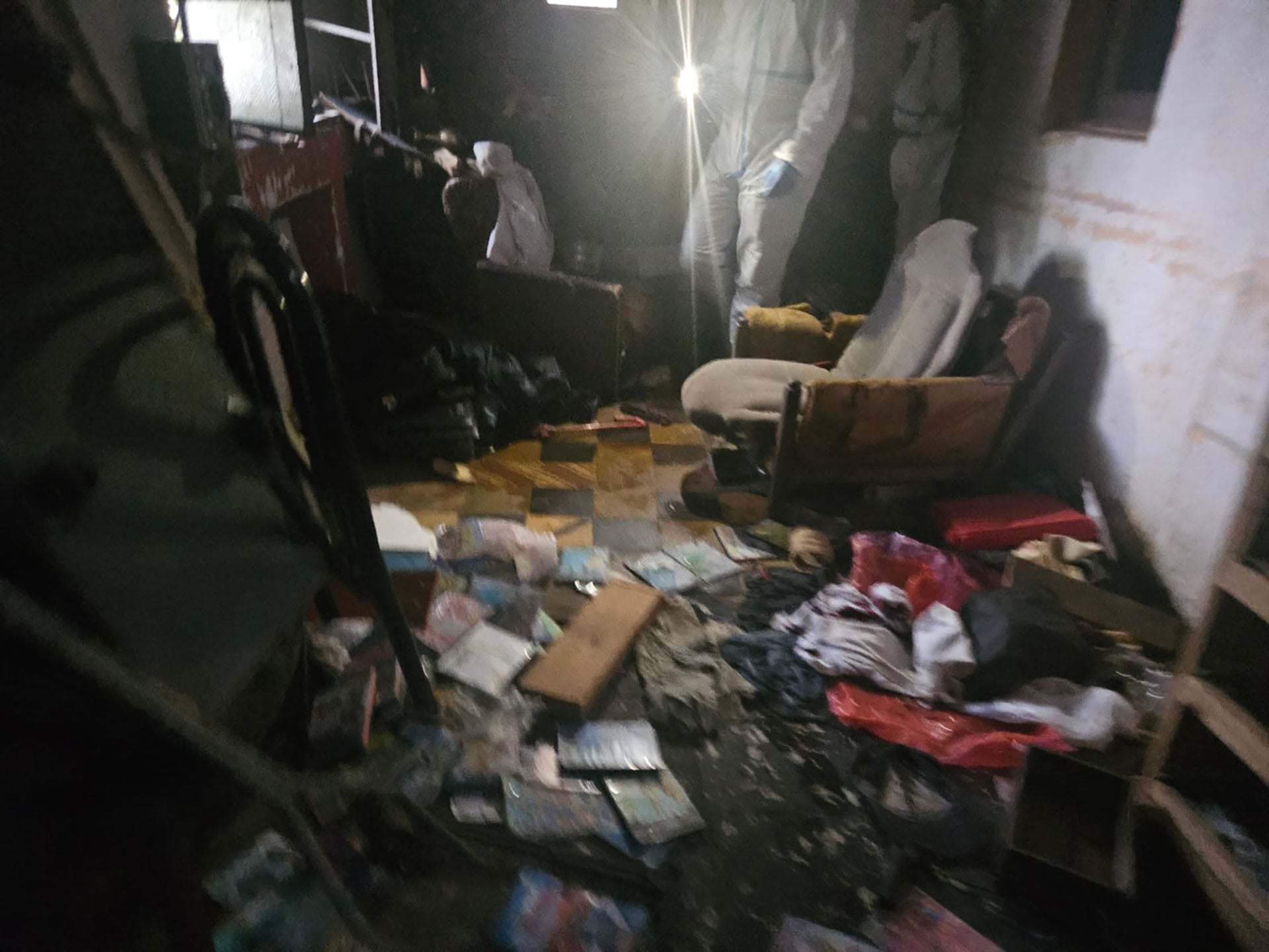 Investigadores forenses inspeccionan meticulosamente una habitación desordenada, parte de la escena del crimen del rapero Mike Dee.