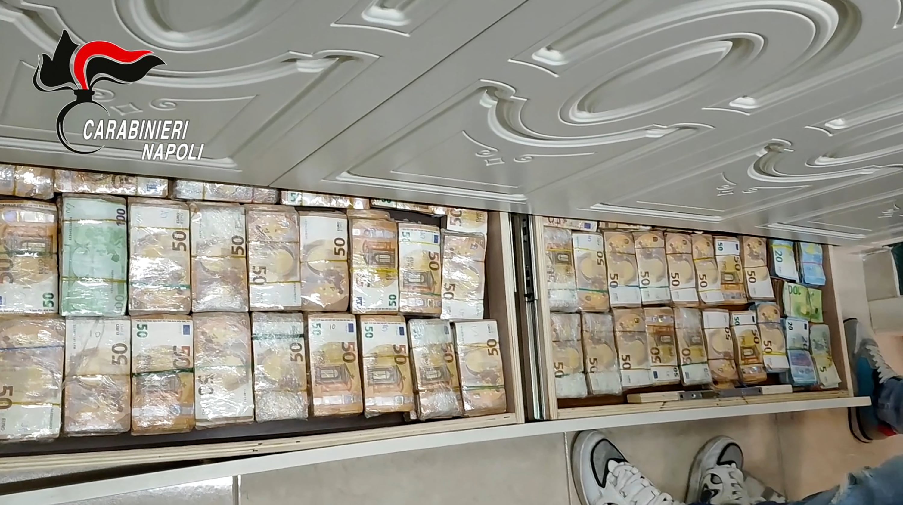 Billetes ocultos en una pared en Caivano, en un operativo que también permitió incautar fusiles Kalashnikov y 11 relojes Rolex (Carabineros italianos/vía AFP)