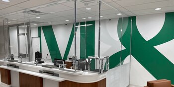 Vista interior de una sucursal bancaria con barreras de seguridad en las cajas, un elemento clave en la prevención de robos y protección del personal frente a amenazas sin uso visible de armas.