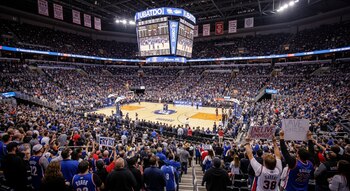 Estadio de baloncesto de la NBA lleno de gente en Estados Unidos. Se ven las gradas repletas, jugadores en la cancha y un gran marcador central suspendido.