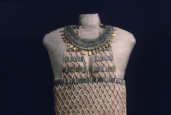 Maniquí de cuerpo parcial que exhibe un vestido de cuentas egipcio con collar ancho de cuentas azules y doradas, y diseño de malla de cuentas