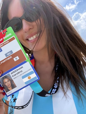 Primer plano de Pampita sonriendo, con gafas de sol y la camiseta argentina. Sostiene una acreditación con su foto, nombre "Carolina Ardohain" y bandera argentina