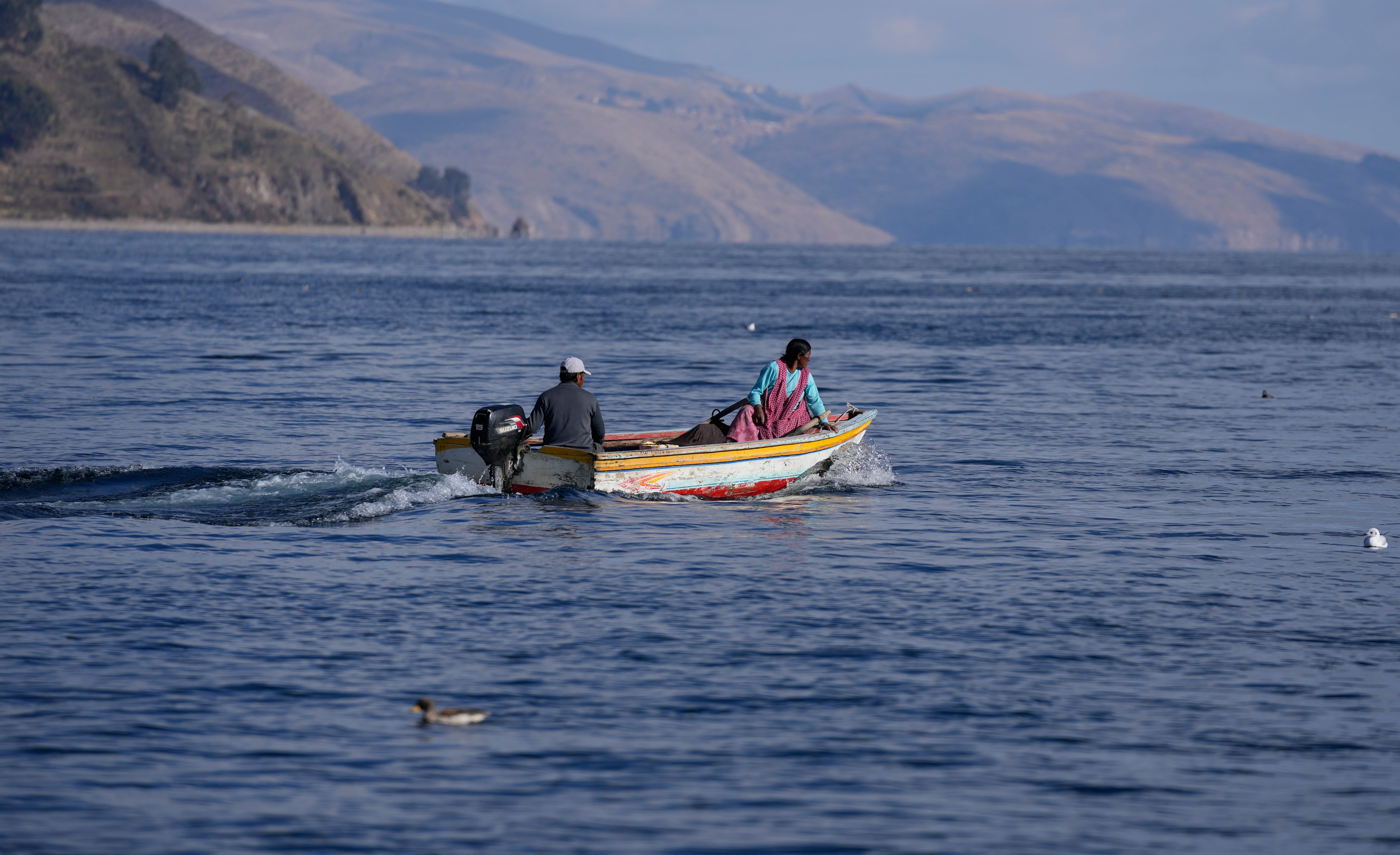 Indígenas aymara navegan en una embarcación en el lago Titicaca, en Tiquina, Bolivia, el 27 de julio de 2023. El bajo nivel del agua en el lago está teniendo un impacto directo en la flora y la fauna locales y afecta a las comunidades locales que dependen de la frontera natural entre Perú y Bolivia para su sustento. (AP Foto/Juan Karita)