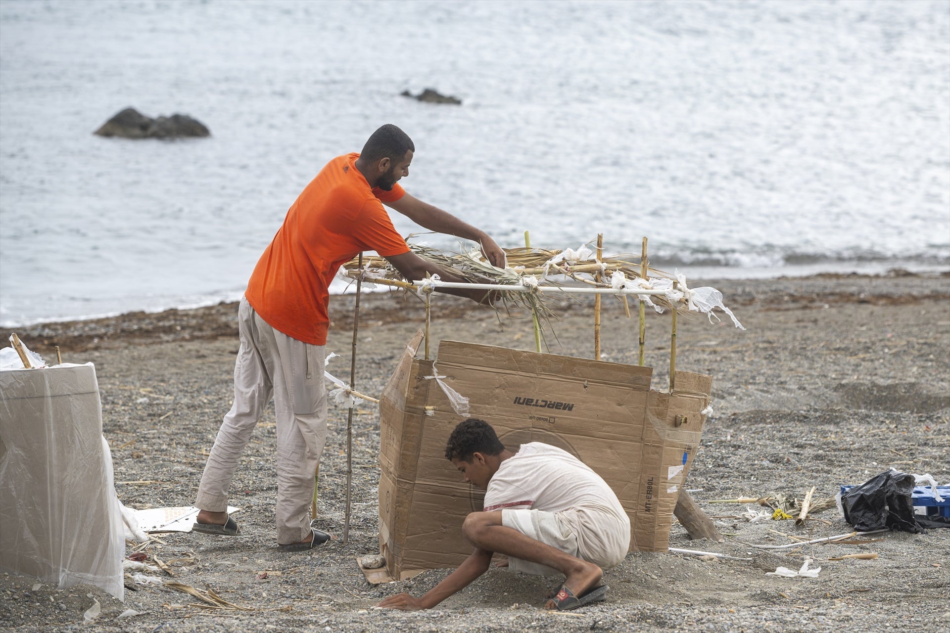 Dos migrantes en la playa El Trampolín en Ceuta. (Marcos Moreno / Europa Press)