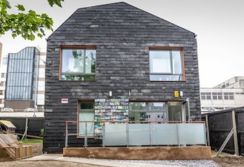 Casa de dos plantas con fachada oscura, ventanas rectangulares, una balaustrada frontal y azulejos decorativos en la parte baja