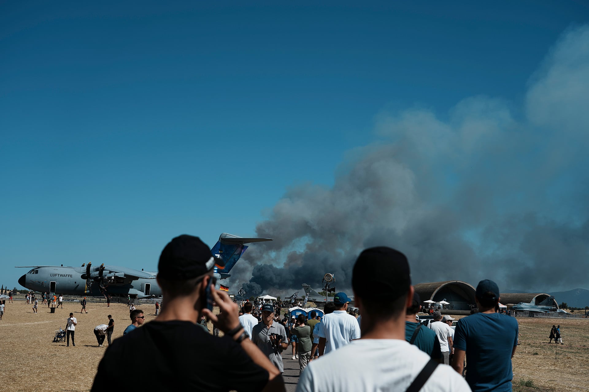 Varias personas presentes en una exhibición aeronáutica en Grecia observan una columna de humo oscuro que se eleva cerca de una aeronave militar. (Ap)