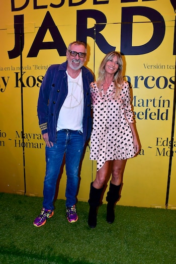 Un hombre y una mujer sonrientes posan de pie frente a un telón amarillo con letras negras "Desde el jardín" y sobre un suelo de césped artificial