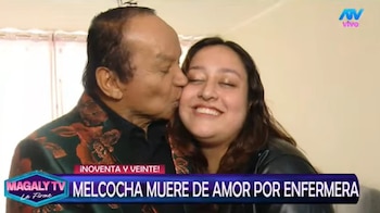 Melcochita, un hombre maduro con traje estampado, besa la mejilla de una mujer joven de cabello oscuro que sonríe con los ojos cerrados. Ambos están en un interior