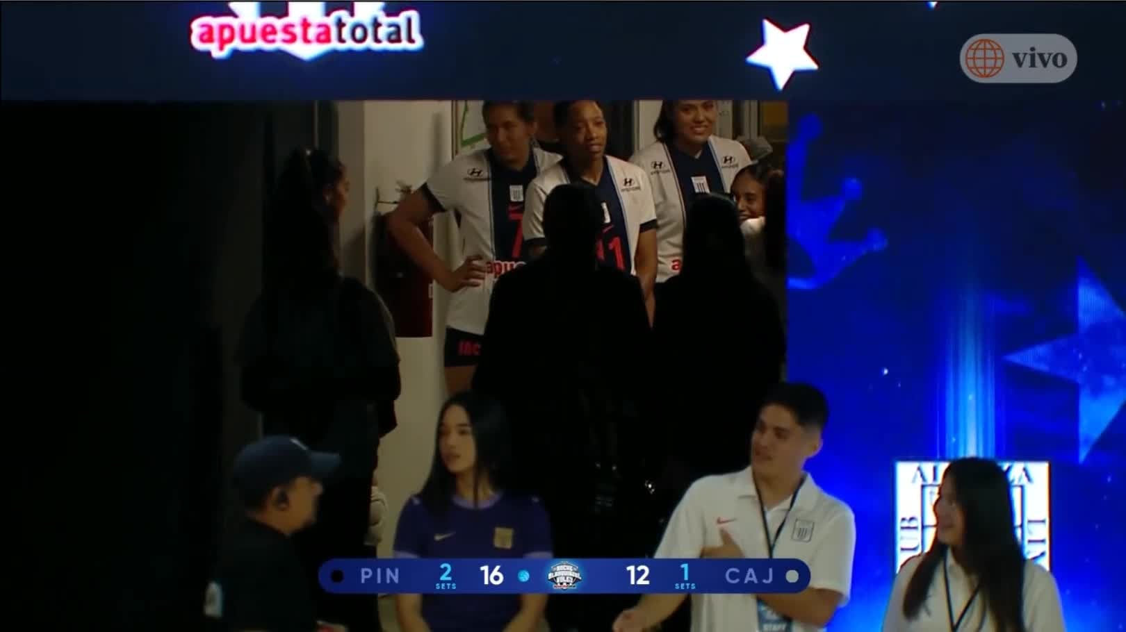 Jugadoras de vóley de Alianza Lima esperan en un pasillo tras la interrupción temporal del encuentro amistoso frente a Boca Juniors durante la Noche Blanquiazul. (América TV)