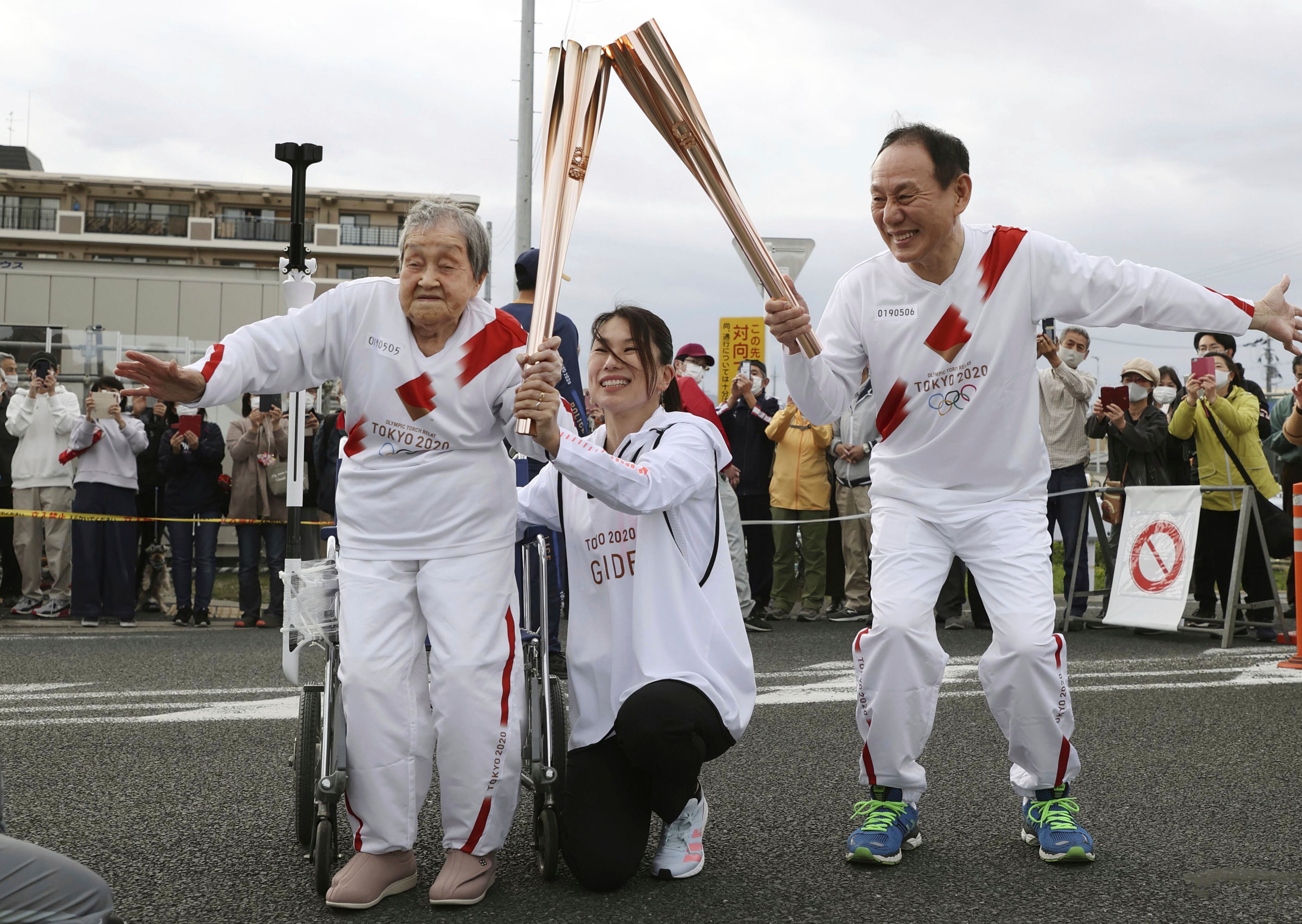 Shigeko Kagawa, a la izquierda, entrega la antorcha olímpica al siguiente corredor durante el relevo de la llama de los Juegos Olímpicos de Tokio, en Yamatokooriyama, Japón, el 12 de abril de 2021. Kagawa, una médica jubilada de 114 años, es la persona viva más anciana de Japón, se informó el 4 de agosto de 2025. (Kyodo News vía AP)
