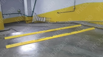 Piso de concreto del Jean Sport Aviation Center con dos barreras de estacionamiento amarillas, paredes amarillas y una escalera apoyada al fondo