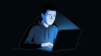 Una persona adulta sentada con el rostro y el torso visibles, usando una computadora portátil en la oscuridad y recibiendo luz azul de la pantalla.