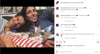 Pietro Sibille y una mujer sonrientes, recostados y apoyando sus cabezas. Un gatito atigrado con ojos claros duerme sobre un cojín de rayas rojas y blancas