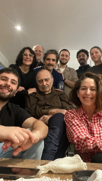 Pepe Novoa sentado en el centro rodeado por varias personas sonrientes en un espacio interior