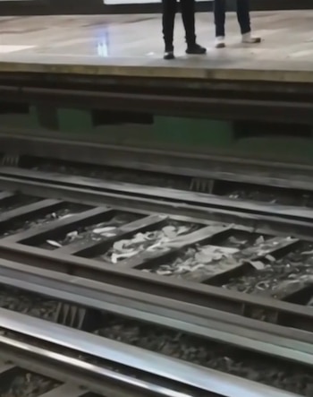 Fragmentos de escombros sobre las vías del metro y personas de pie en el andén superior
