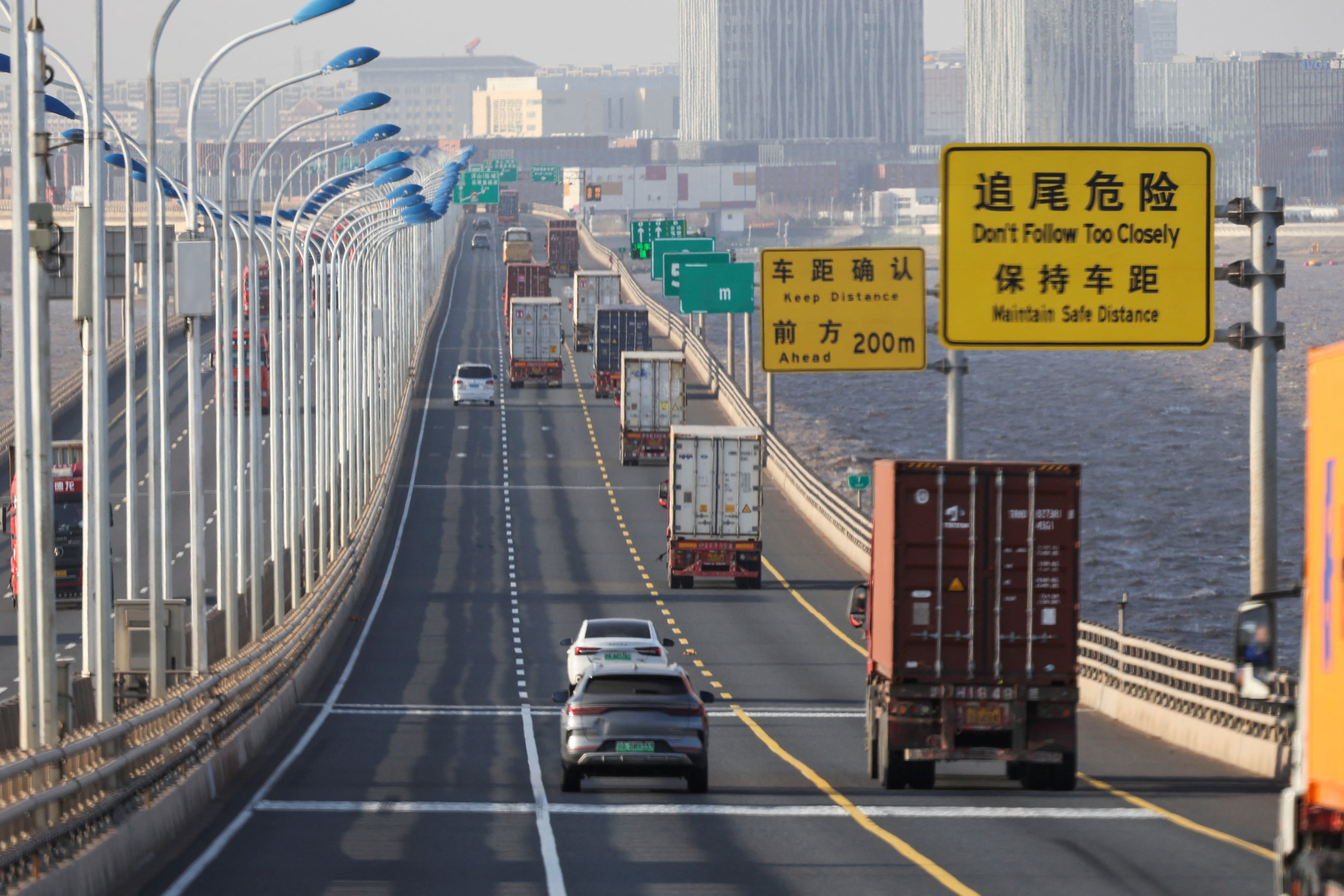 Camiones pasan por el puente Donghai para salir del puerto de Yangshan en las afueras de Shanghái (Go Nakamura / Reuters)