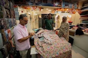 Unas personas examinan telas bordadas en una tienda de textiles de un bazar tradicional en Bandar Abbas, Irán, el domingo 6 de septiembre de 2026 (AP/Vahid Salemi)