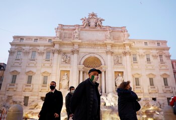 Italianos con máscaras faciales caminan